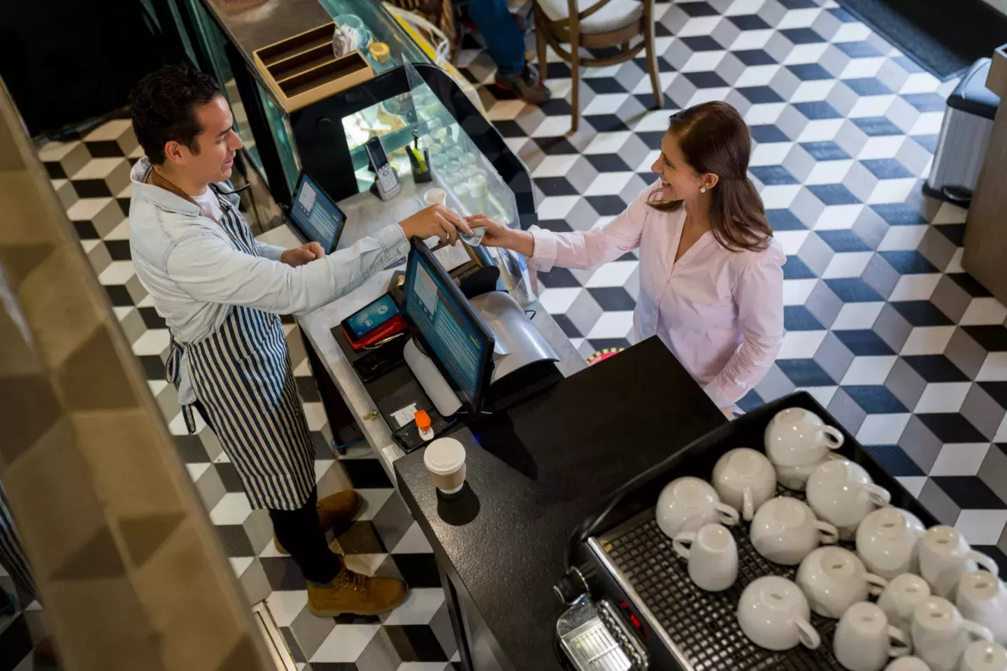 Woman at a cafe buying a cup of coffee to go and paying by cash